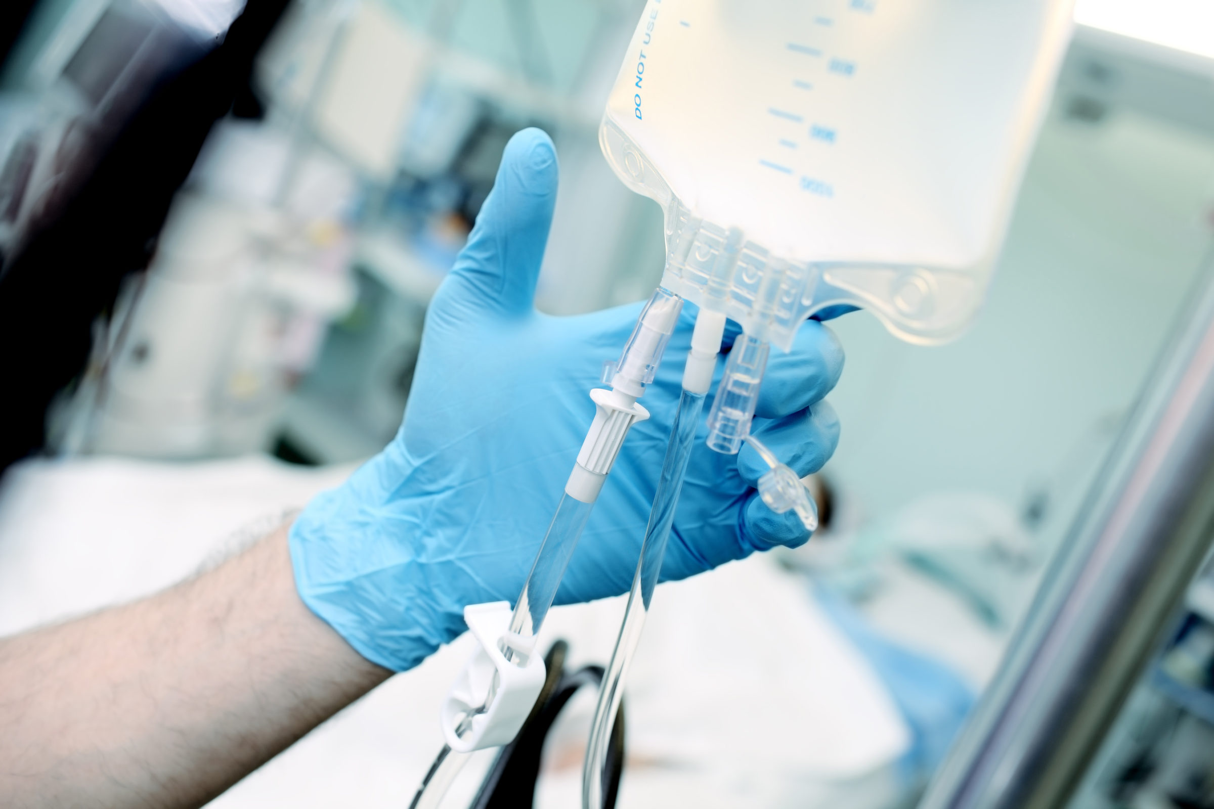 Male medical worker regulate the intravenous drip system at the patient bed in the critical care unit