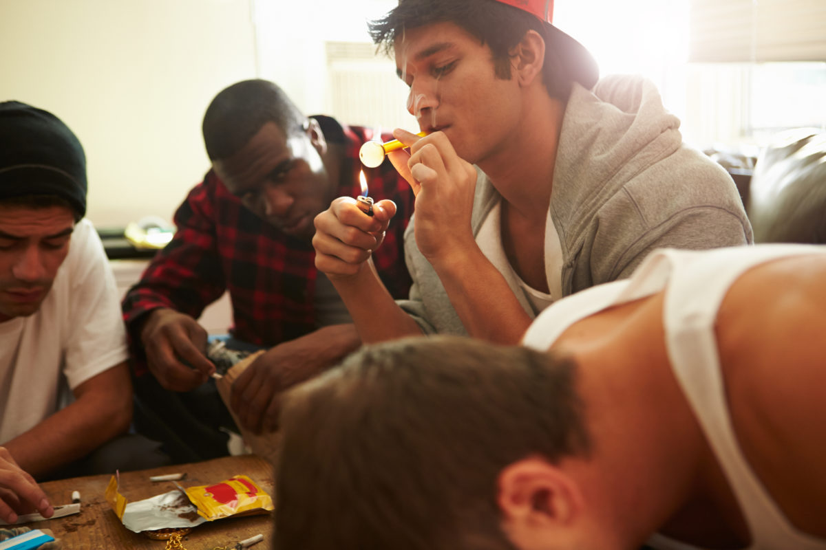 Gang Of Young Men Taking Drugs Indoors