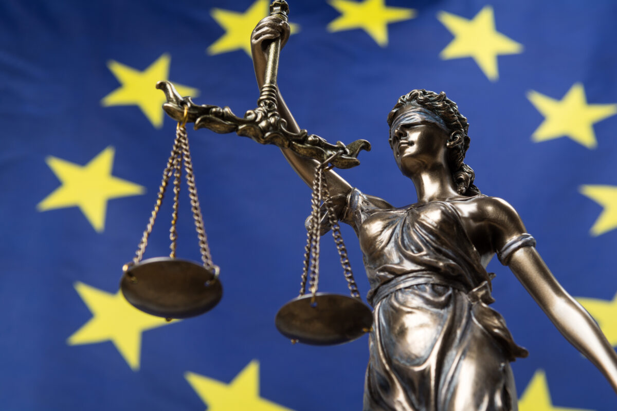 Statue of the blindfolded goddess of justice Themis or Justitia, against an European flag, as a legal concept