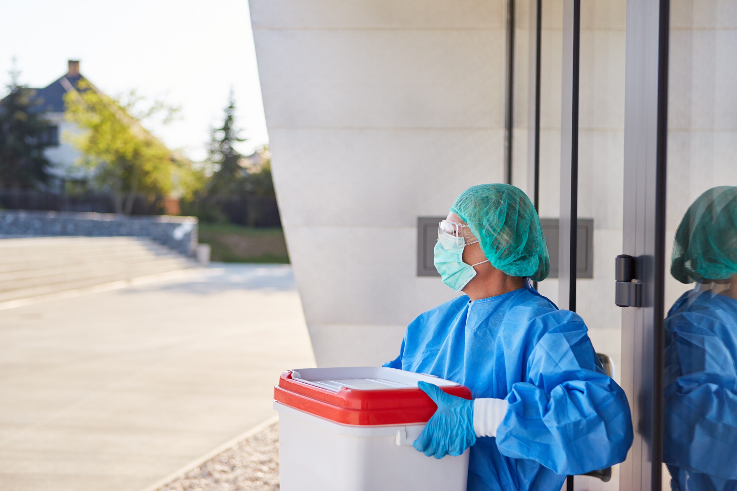 Surgeon with organ transport after organ donation in front of clinic entrance