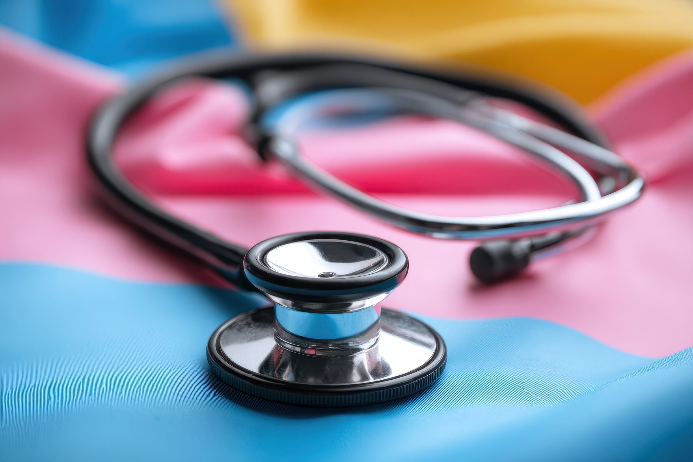 Transgender Care: Stethoscope on LGBT Flag Background - Healthcare and Business Concept
