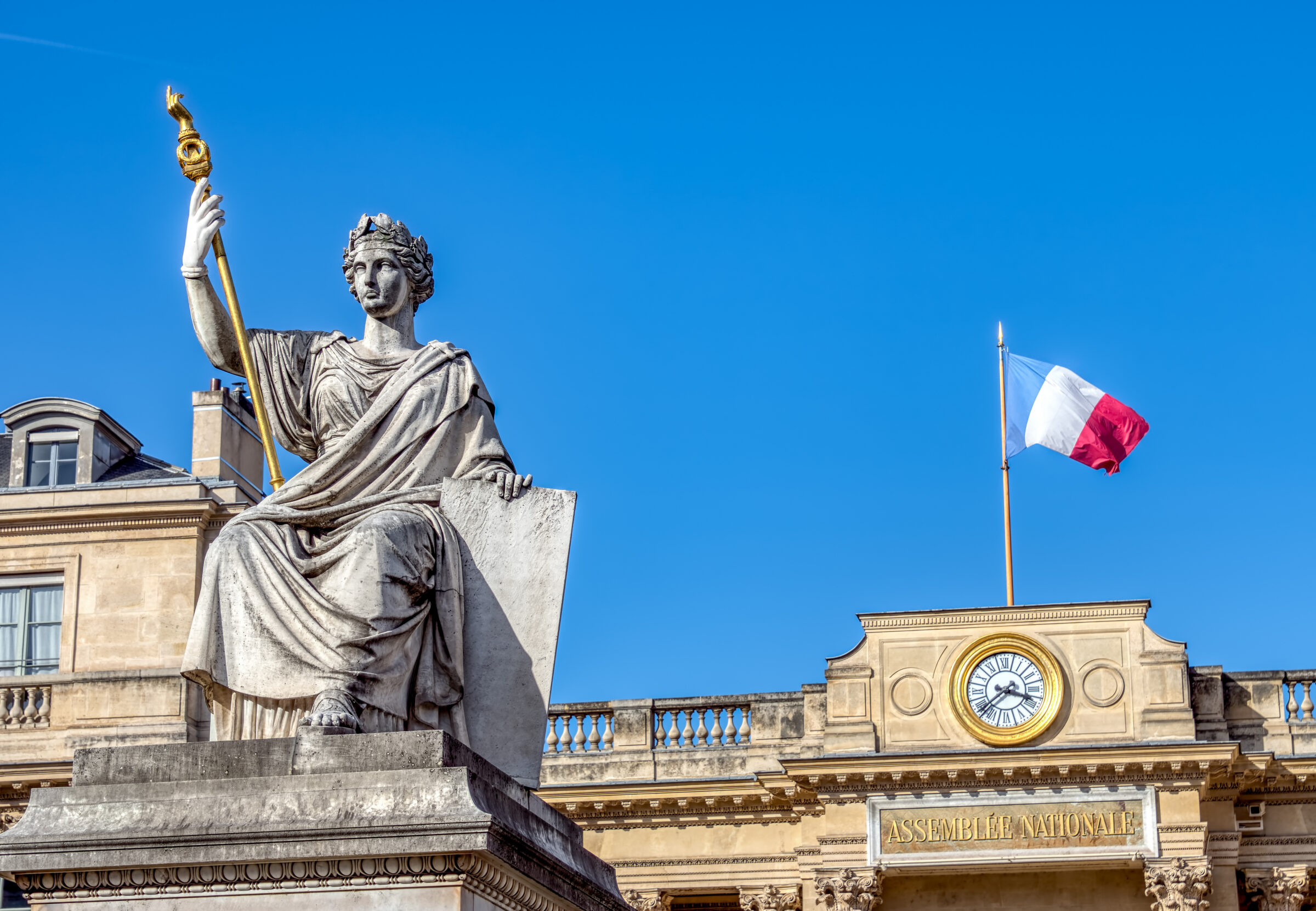 Clock on rear entrance of French National Assembly, aka Palais Bourbon, with Law statue in foreground.
